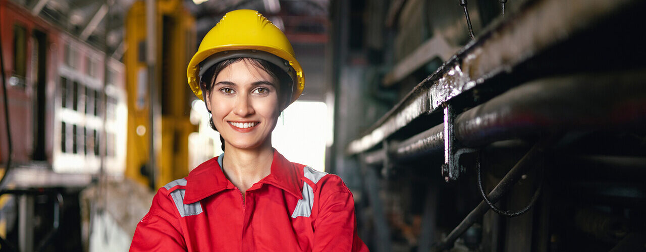 engineering women in safety uniform operating machine at factory industrial and standing with smiling in workplace