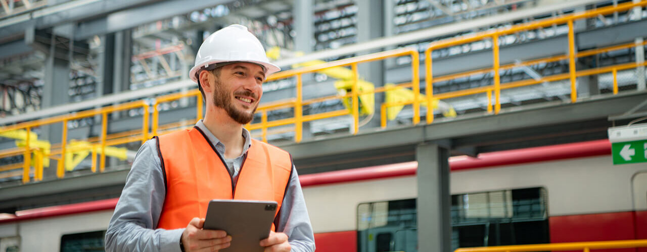 Portrait of a young male technician using a walkie talkie working and standing in a skytrain repair station.